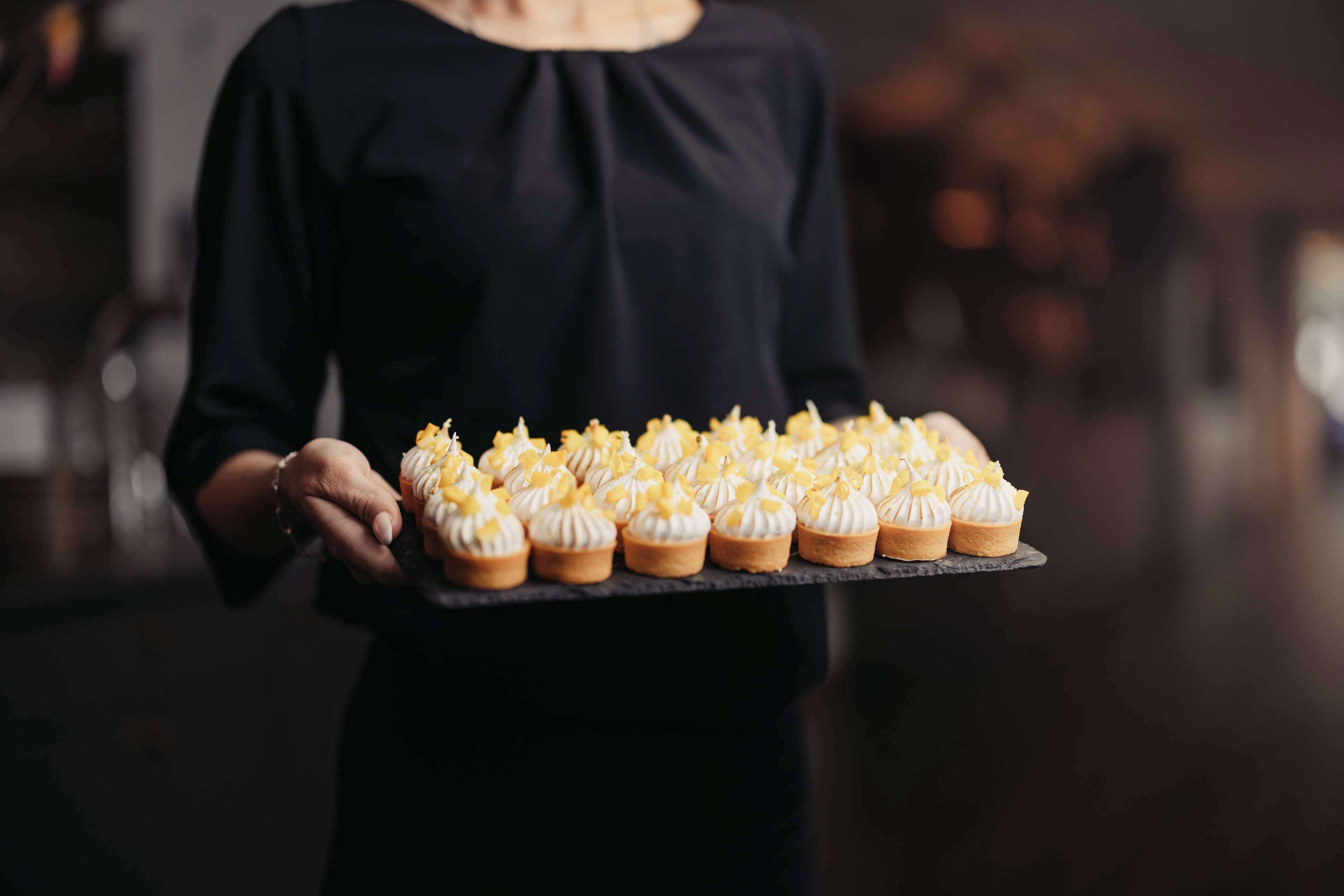 A person holding a tray with multiple cupcakes.