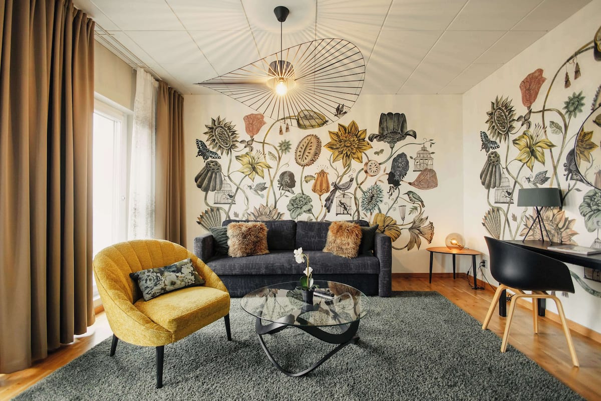 Un salon comprenant un canapé, un fauteuil, une table basse et une fresque murale.