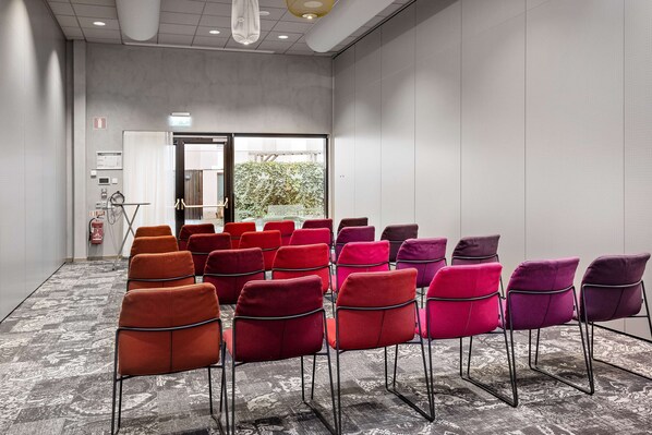 A conference room with rows of chairs, a fire extinguisher, and a door leading outside.