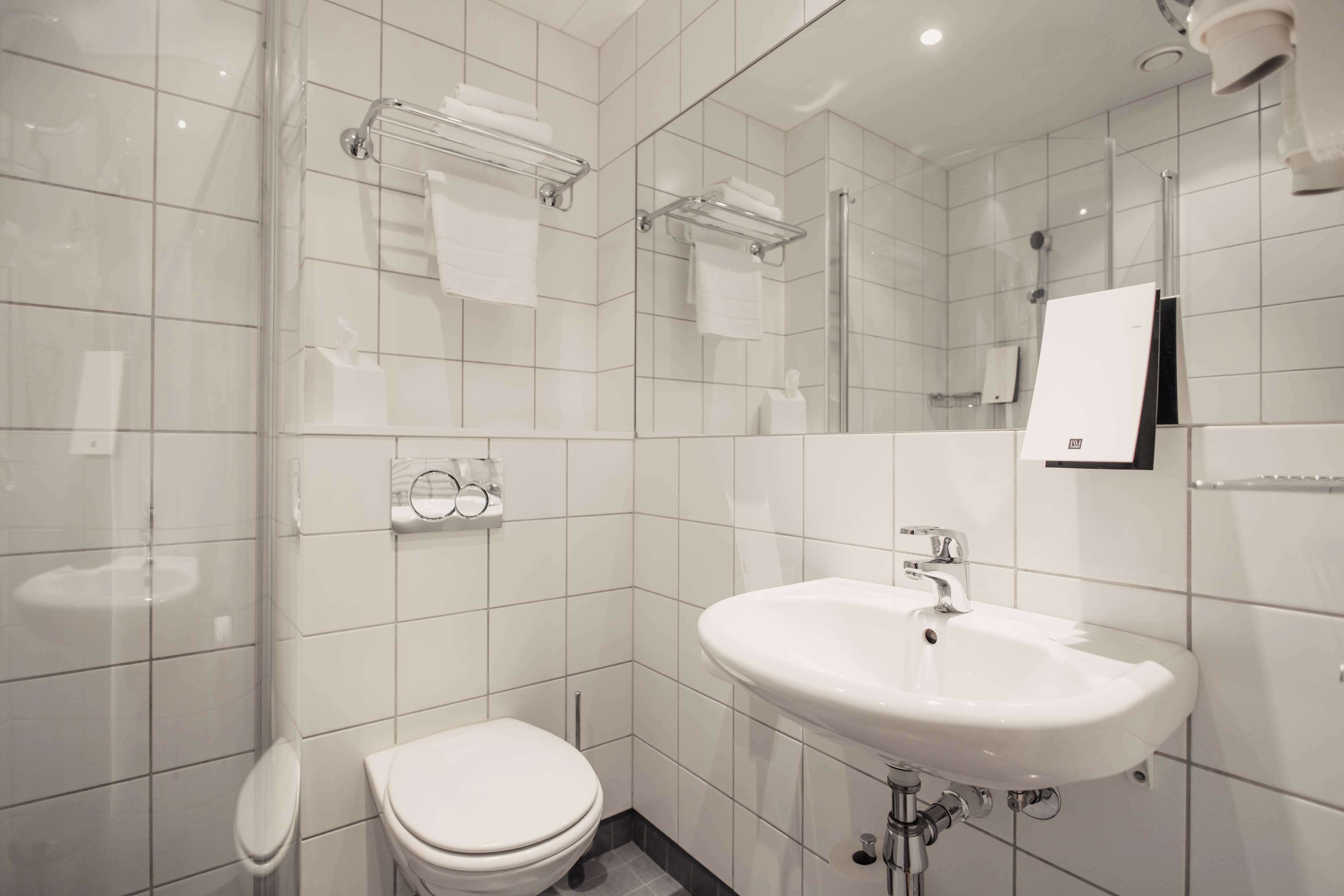 A modern bathroom with a white sink, toilet, and glass shower enclosure.