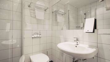 A modern bathroom with a white sink, toilet, and glass shower enclosure.