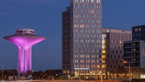Un hotel de diseño moderno, con una estructura imponente en forma de torre con ventanas iluminadas y un letrero que dice “HOTEL”.