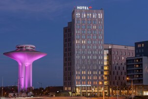 Un hotel de diseño moderno, con una estructura imponente en forma de torre con ventanas iluminadas y un letrero que dice “HOTEL”.