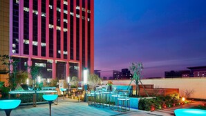Fachada moderna de hotel con un edificio grande, zona de estar exterior y senderos bien iluminados.
