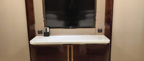 A minibar with a flat-screen TV, a remote control, and a small electrical outlet.