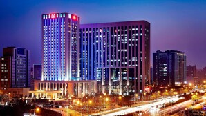 Un hotel de gran altura con varios pisos, un letrero llamativo en la parte superior y una fachada bien iluminada.