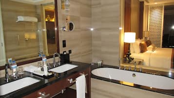 Un baño con dos lavamanos, una bañera y un espejo grande.