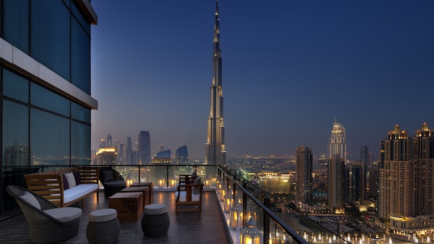 Une terrasse sur le toit offrant une vue sur le Burj Khalifa, dotée de mobilier moderne et donnant sur le paysage urbain au crépuscule.