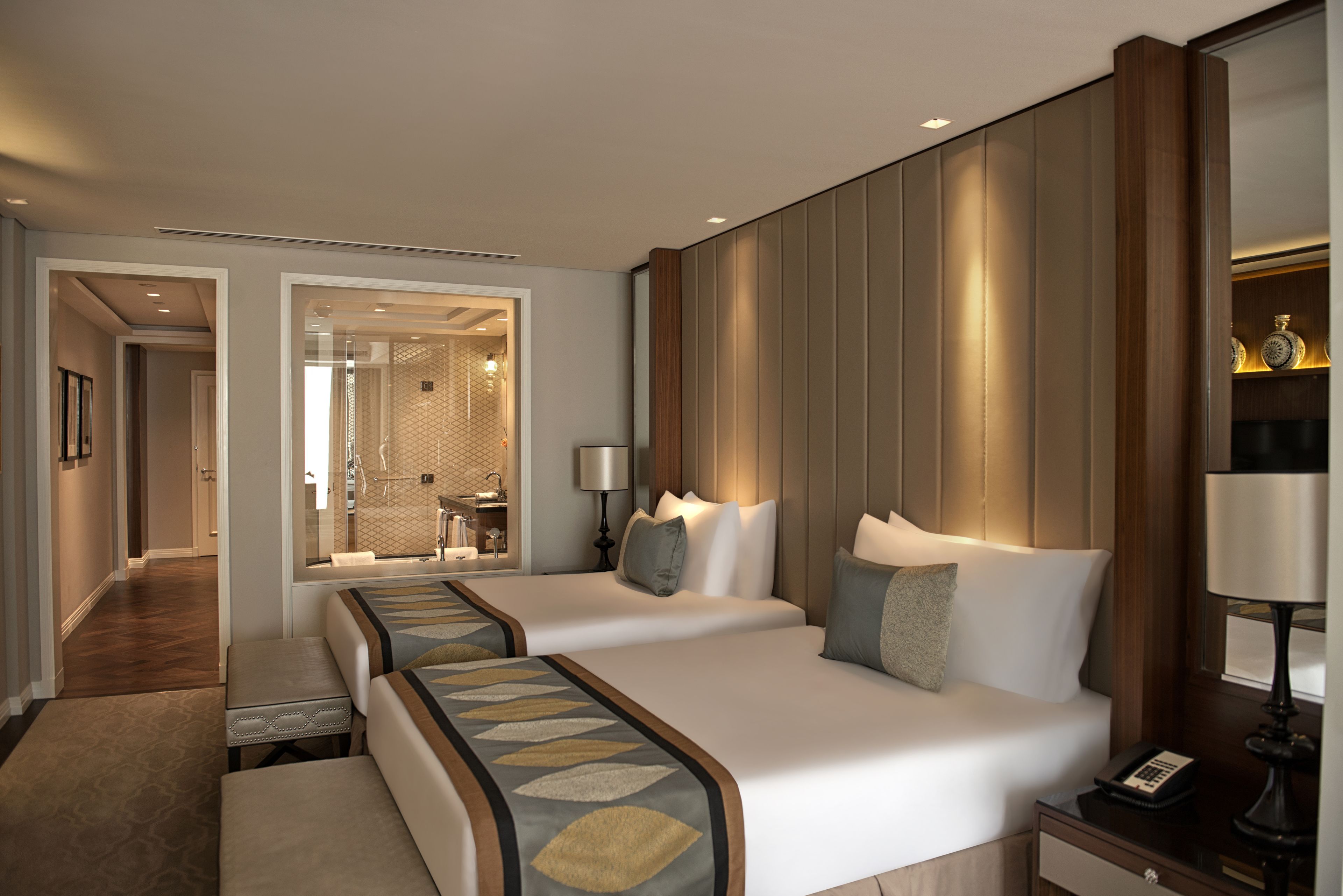 Habitación de hotel con dos camas, un baño y un pasillo que conduce a otra habitación.