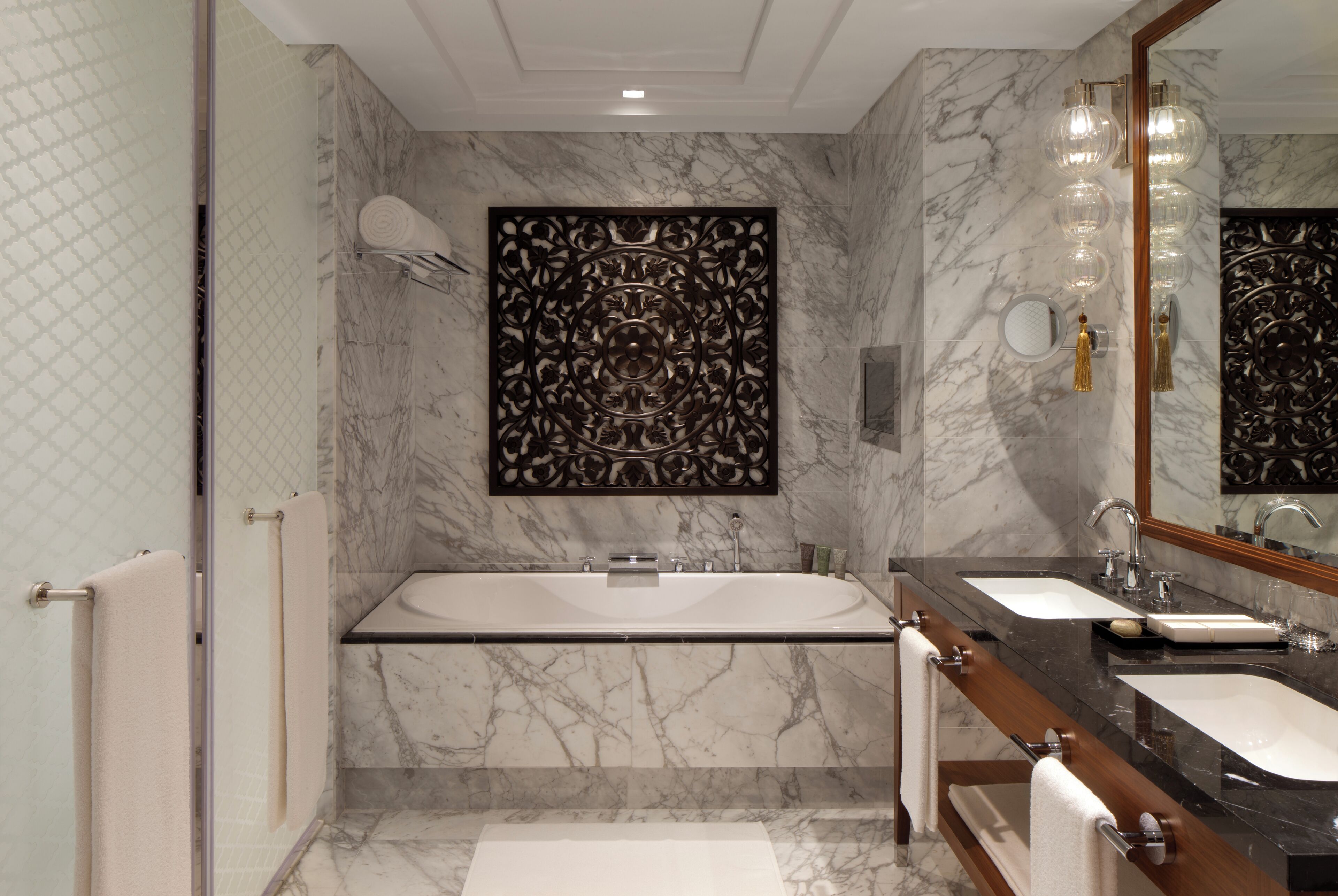 Un bagno moderno con pavimento in marmo, una vasca da bagno freestanding, due lavandini e un grande specchio.