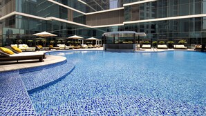 Une piscine intérieure moderne, avec des carreaux de mosaïque bleu clair, des chaises longues et des parasols.