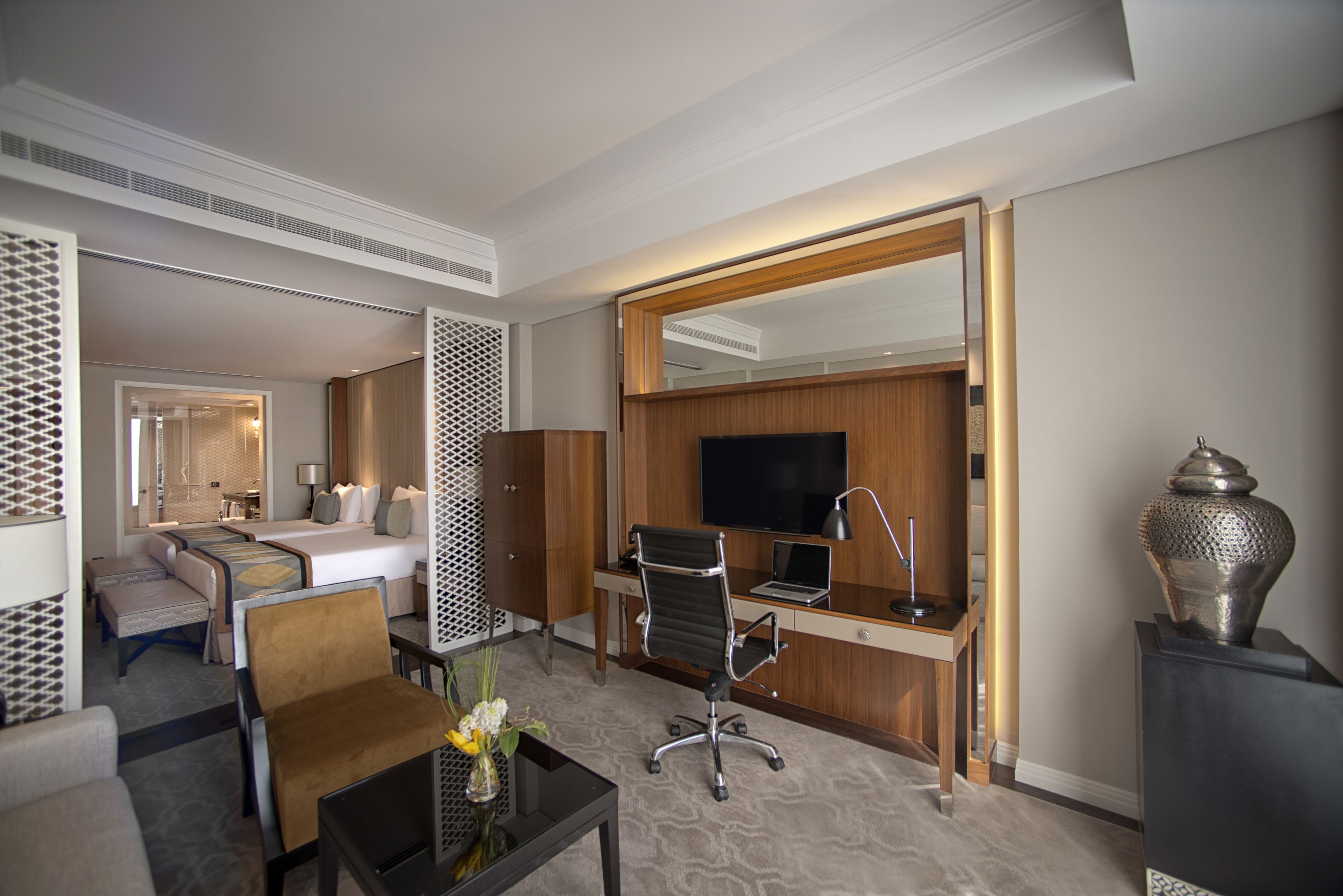 Une chambre d’hôtel équipée d’un lit, d’un bureau, d’une chaise, d’une télévision et d’un vase décoratif.
