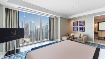 A modern hotel room with a large bed, a sofa, a TV, and a city view.