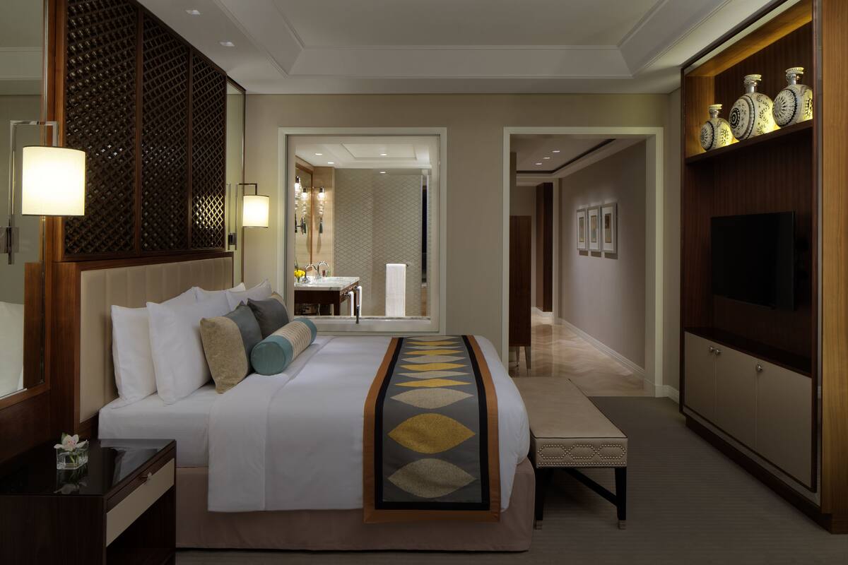 A hotel room with a large bed, bedside table, lamp, and a TV on a wooden cabinet.