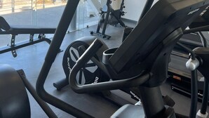 A gym with cardio equipment, a TV on the wall, and large windows offering a view of the outside. - Hotel VM Express Querétaro (Querétaro)