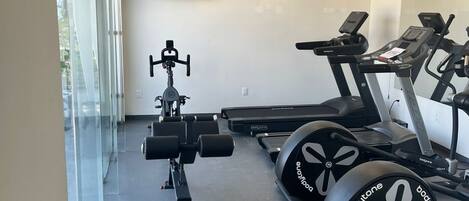 Un gimnasio con cintas de correr, una bicicleta estática y máquinas de pesas.