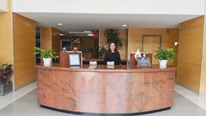 A reception desk with a marble top, potted plants, and a framed welcome sign. - Hotel VM Express Querétaro (Quer étaro)