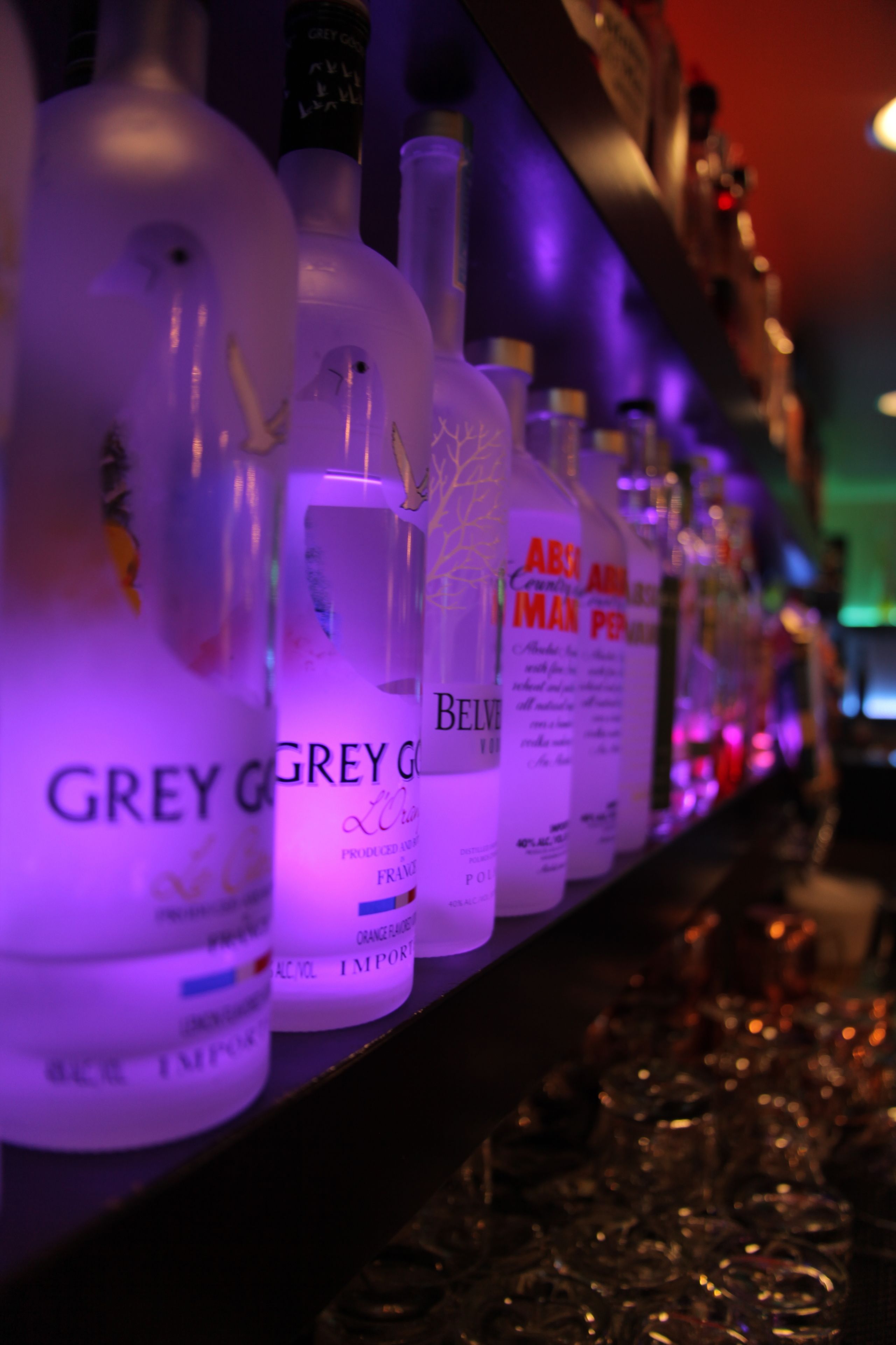 Bottles of Grey Goose vodka lined up on a shelf.