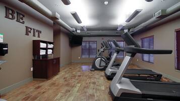 A hotel fitness room with treadmills, a stationary bike, and a wall sign that says "BE FIT".