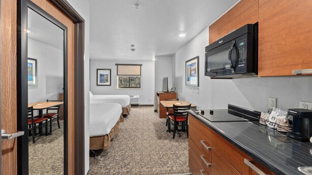 A compact hotel room with a kitchenette, a bed, a desk, and a small dining area. - MainStay Suites Spokane Valley (Spokane Valley)