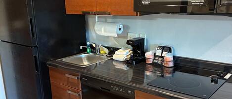 A compact kitchen with a refrigerator, microwave, dishwasher, and a sink.
