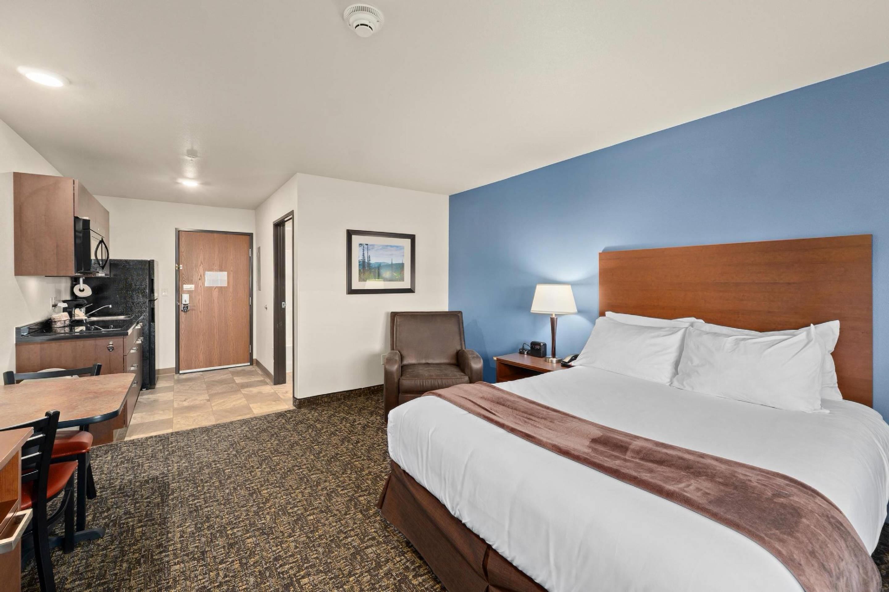 Une chambre d’hôtel équipée d’un lit, d’un bureau, d’une chaise et d’une kitchenette.