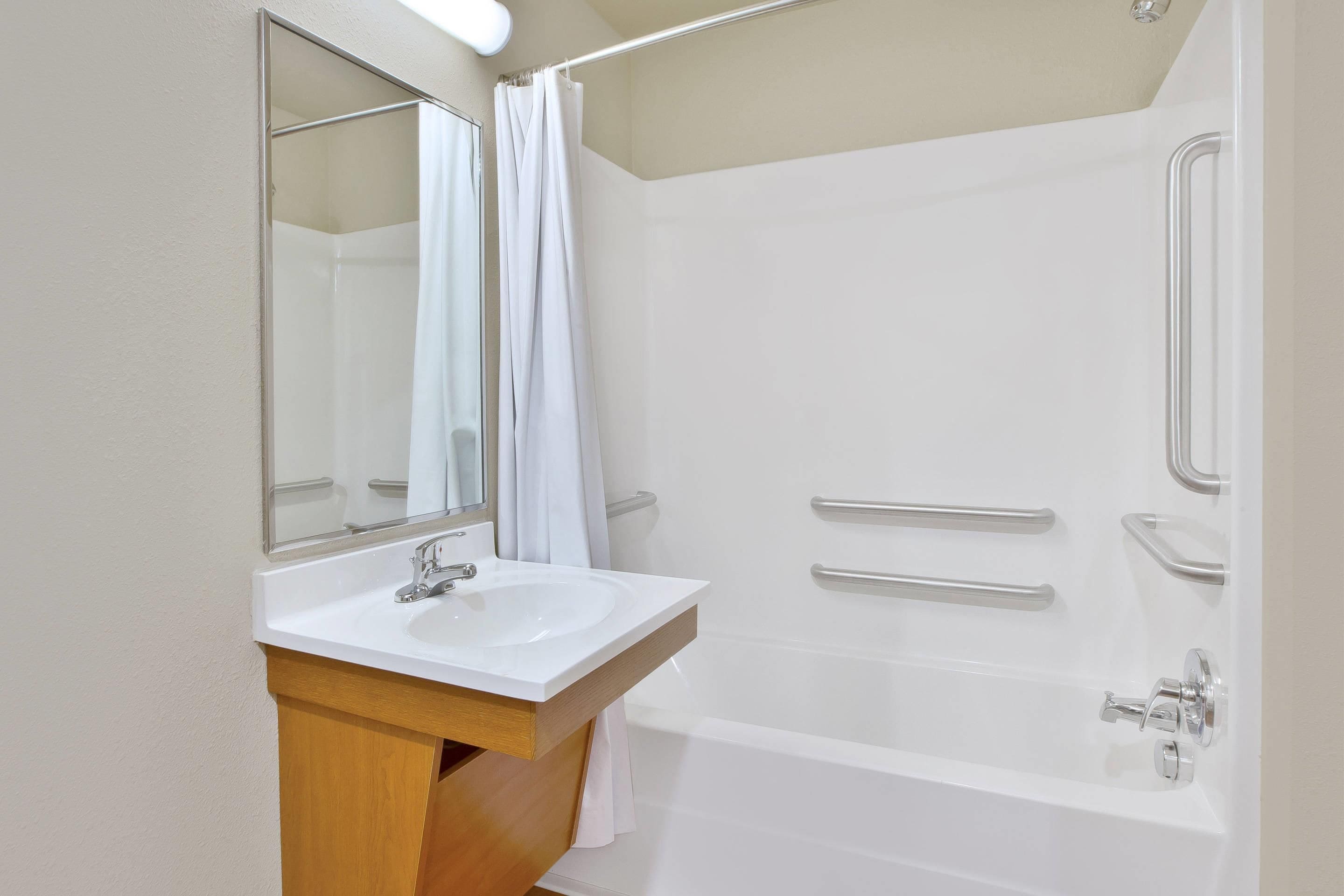 A bathroom with a white sink, mirror, and bathtub.