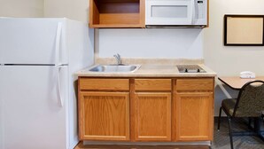 Eine kompakte Küche mit Kühlschrank, Mikrowelle, Spüle und Holzschränken.
