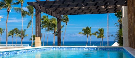 Una piscina al aire libre, sombrillas, sillones reclinables de piscina