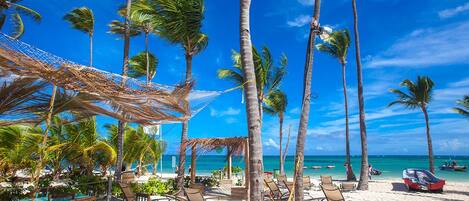 Rannalla, valkoista hiekkaa, aurinkotuoleja, rantapyyhkeitä