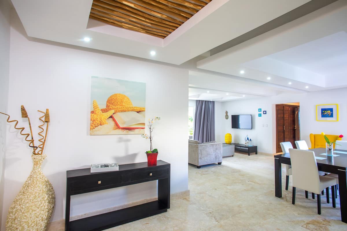 A modern living room with a sofa, dining table, and artwork on the wall.