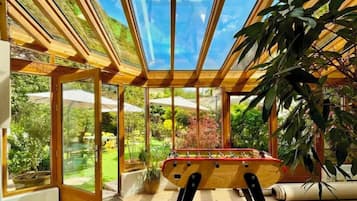 A room with a foosball table, large windows, and a view of the outdoors.