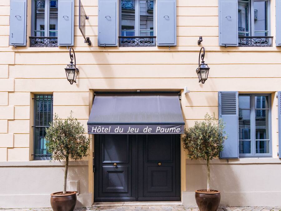 Un edificio con un toldo negro y un cartel que dice 'Hôtel du Jeu de Paume'.