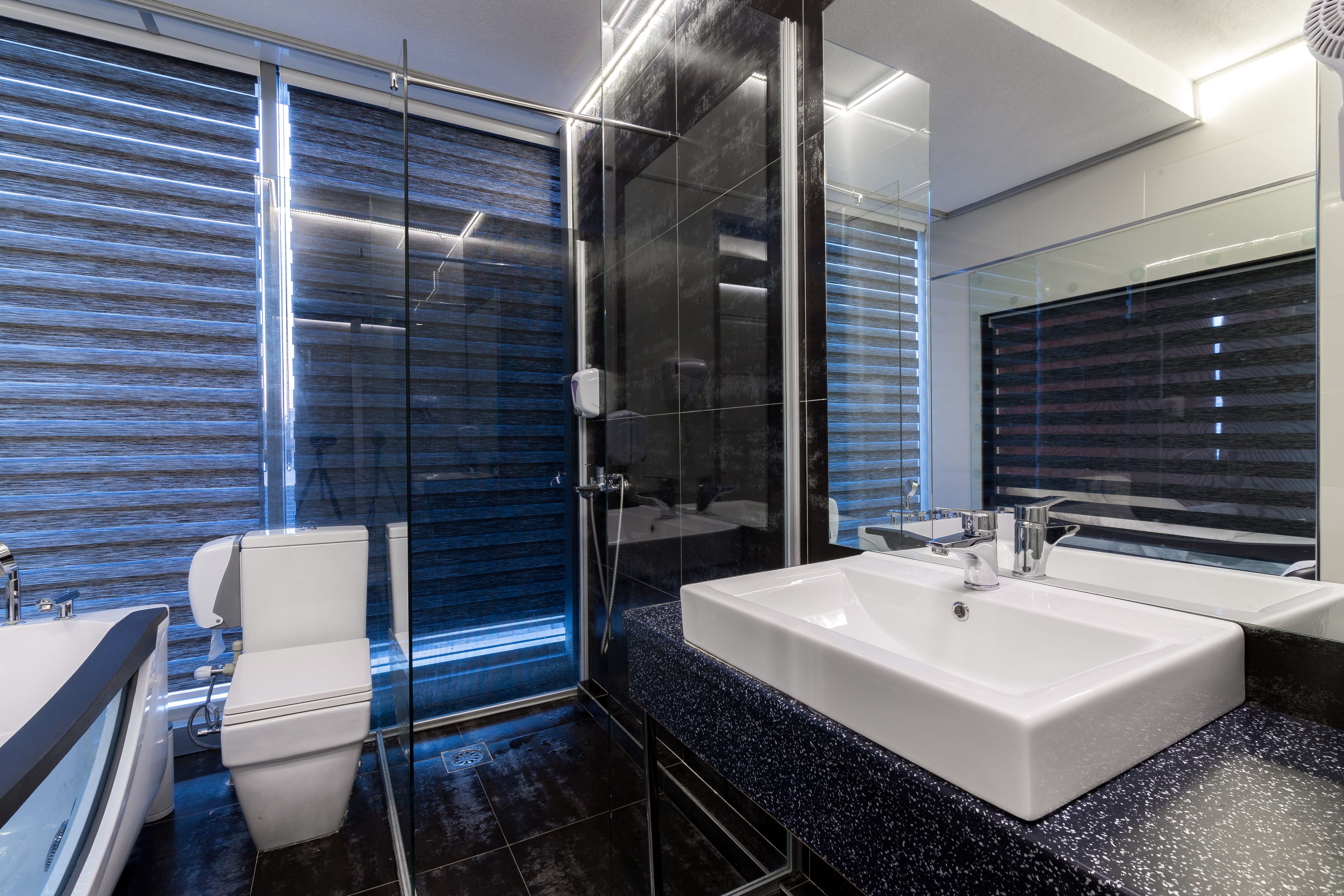 A modern bathroom with a glass shower enclosure, a white toilet, and a large sink with a mirror.