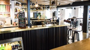 A bar area with a counter, stools, and shelves with bottles.