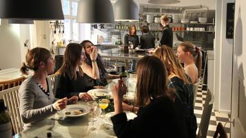 Un grupo de personas cenando en una mesa en una cocina moderna con iluminación colgante y piso a cuadros.