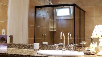 A modern bathroom with a glass-enclosed shower, a white sink, and a marble countertop.