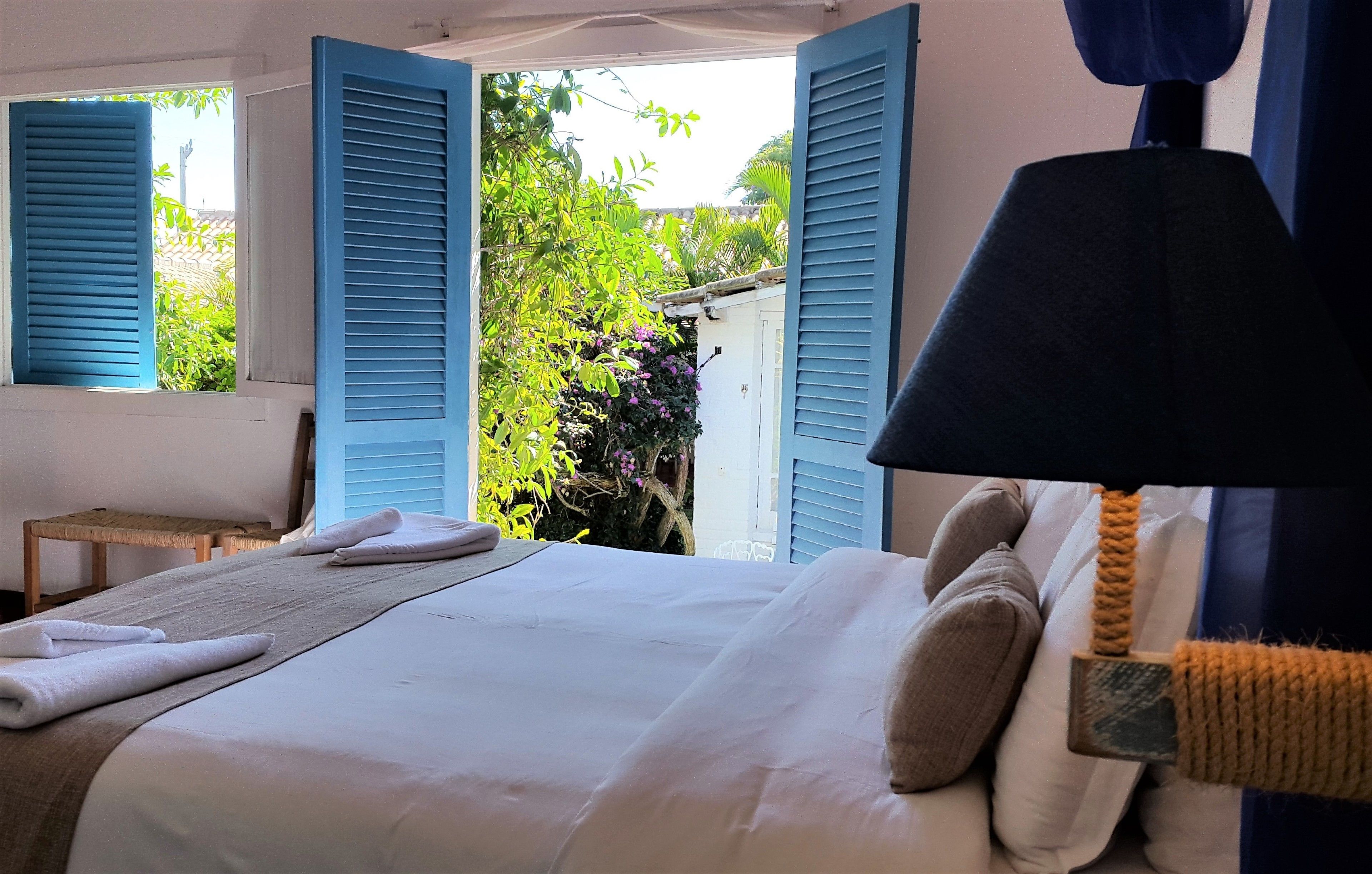 Una camera da letto con un letto, asciugamani, una lampada e vista sul verde circostante.