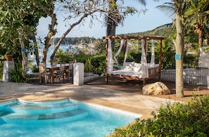 Una piscina al aire libre, sombrillas, sillones reclinables de piscina