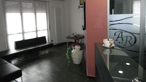 A modern interior with a seating area, a reception desk, and a large window. - Albergo Renato (Sesto San Giovanni)