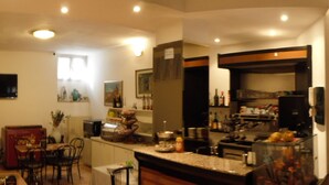 A kitchen with a dining area, equipped with a refrigerator, stove, and various kitchen appliances. - Albergo Renato (Sesto San Giovanni)