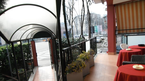 A restaurant with outdoor seating, a covered walkway, and potted plants. - Albergo Renato (Sesto San Giovanni)