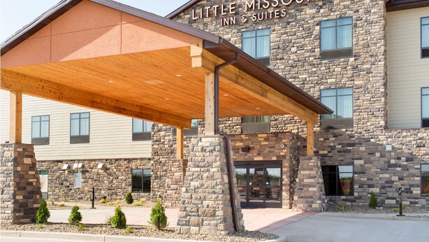 A hotel with a stone facade and a covered entrance area. - Little Missouri Inn & Suites (Watford City)