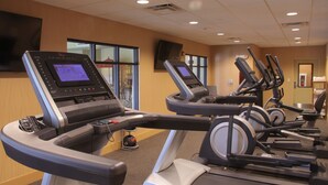 A gym with treadmills and stationary bikes, a TV mounted on the wall, and windows allowing natural light. - Little Missouri Inn & Suites (Watford City)