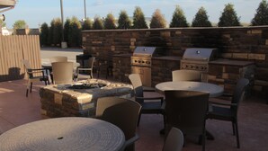 Eine Terrasse im Freien mit Steinmauern, einem Grill und Korbmöbeln.