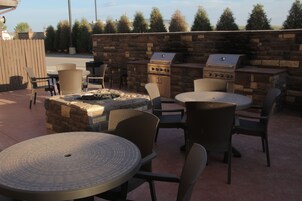 Un patio al aire libre con paredes de piedra, una parrilla y mobiliario de mimbre.