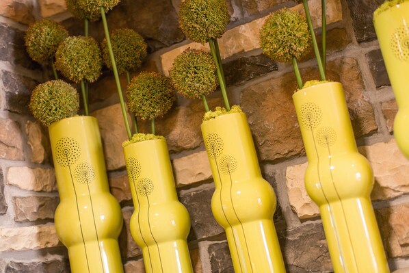 A row of yellow vases with spherical tops, each containing a green plant, against a stone wall background. - Little Missouri Inn & Suites New Town (New Town)