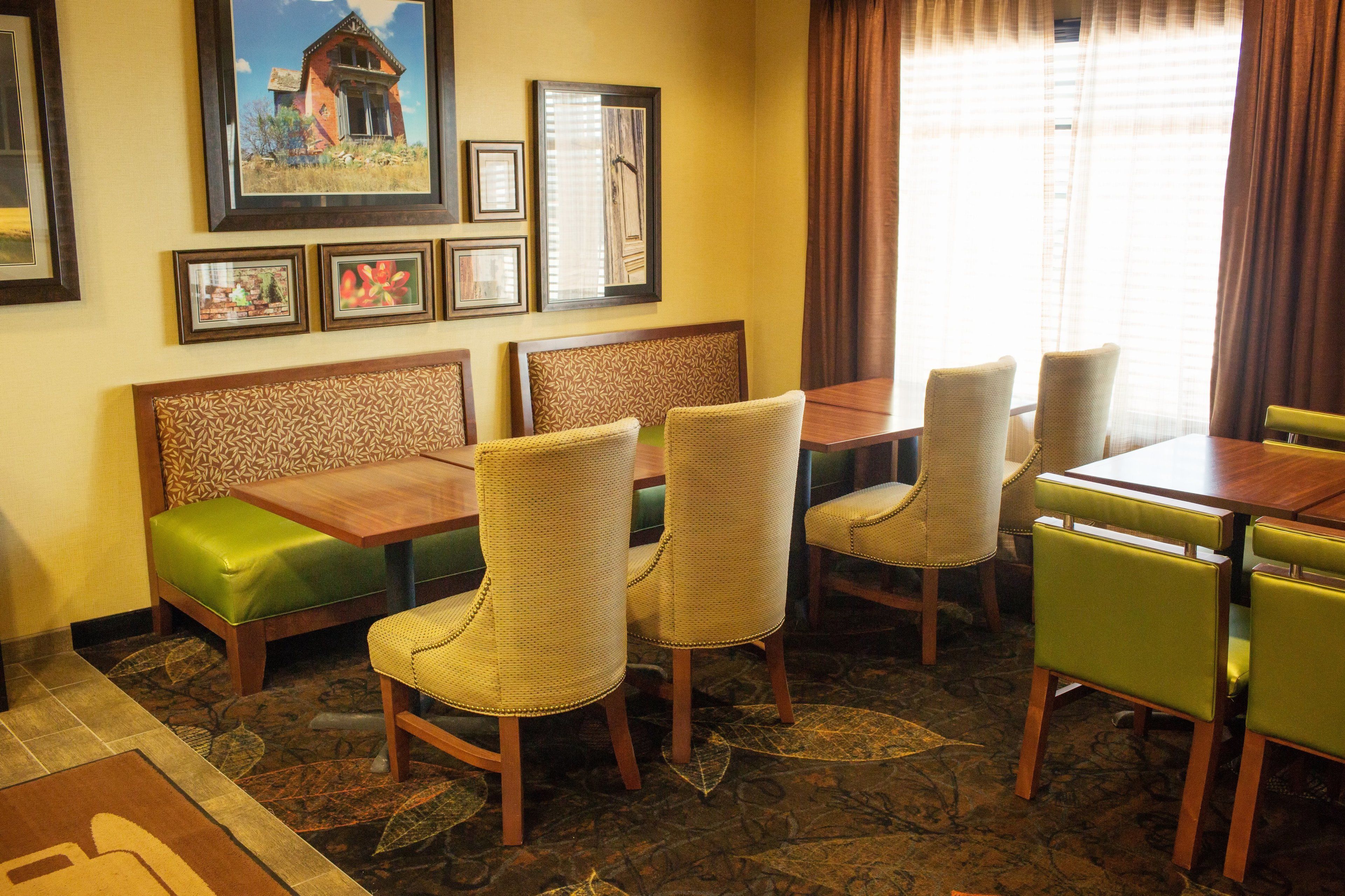 A dining area with a wooden table and chairs, a green cushioned bench, and framed pictures on the wall.