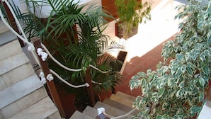A staircase with a rope handrail, surrounded by potted plants and a wooden door. - Pousada Casa das Rosas (Búzios)