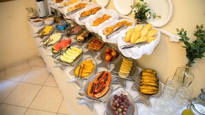 A buffet table with various fruits, cheeses, and bread. - Pousada Casa da Praia (Búzios)